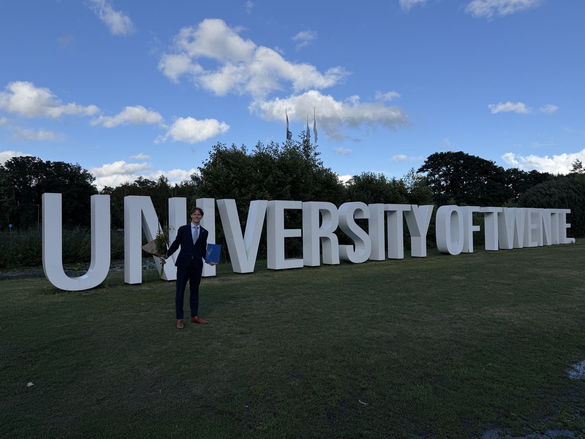 Beau at the University of Twente sign after the defense, 28 August 2026